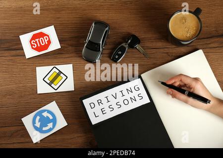 Femme avec guide pour les leçons de conduite et une tasse de café à une table en bois, vue de dessus. Réussite de l'examen de licence Banque D'Images