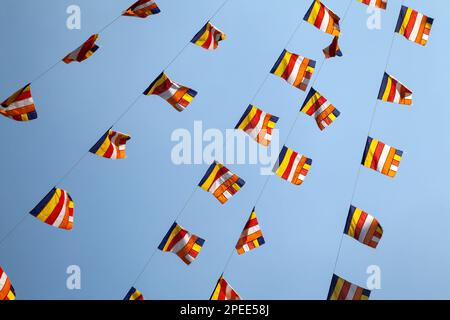 De nombreux drapeaux bouddhistes colorés ont volé dans le ciel dans une pagode au Vietnam. Version officielle d'un drapeau bouddhiste rayé vu dans un temple asiatique Banque D'Images