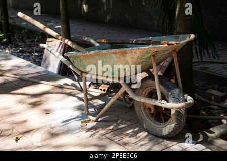 Vieille brouette sale avec des outils à l'intérieur, laissée sur un chantier de construction. barre à roue simple extra-robuste avec poignées, équipement pour entrepreneurs Banque D'Images