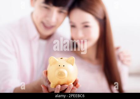 Couple heureux tenant Piggybank et faisant des économies pour l'avenir Banque D'Images