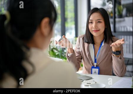 Femme d'affaires asiatique ou recruteur des ressources humaines attirante et professionnelle du millénaire qui interviewe un candidat au bureau. Banque D'Images