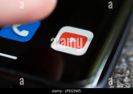 Un smartphone allongé sur une table dans le noir, affichant le logo de YouTube. Le doigt au-dessus de l'écran tactile. Barnaul. Russie 20 juin 2022 Banque D'Images