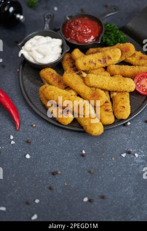 Bâtonnets de fromage Mozzarella cuits avec sauce tartare et tomate rouge sur une assiette Banque D'Images