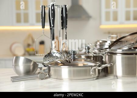 Ensemble d'ustensiles de cuisine brillants sur une table dans la cuisine Banque D'Images