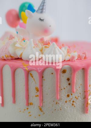 gâteau d'anniversaire blanc givré rose givré avec licorne, meringue et saupoudrés, peinture comestible dorée coups de pinceau sur le support Banque D'Images