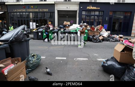 Paris, France. 15th mars 2023. Les ordures sont vues à gauche dans la rue de Paris, France, 15 mars 2023. Il est probable que les ordures continuent de s'accumuler dans la capitale, puisque les collecteurs de déchets et les nettoyeurs de rue seront en grève jusqu'à 20 mars. Selon l'hôtel de ville, environ 76 000 tonnes de déchets seront collectés mercredi à Paris. Credit: Gao Jing/Xinhua/Alamy Live News Banque D'Images