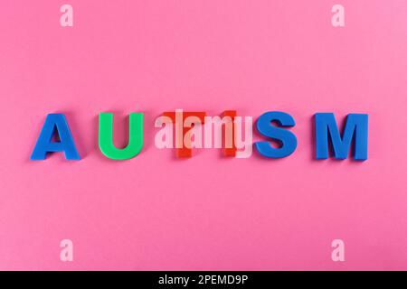 Mot autisme fait avec des lettres colorées sur fond rose, vue de dessus Banque D'Images