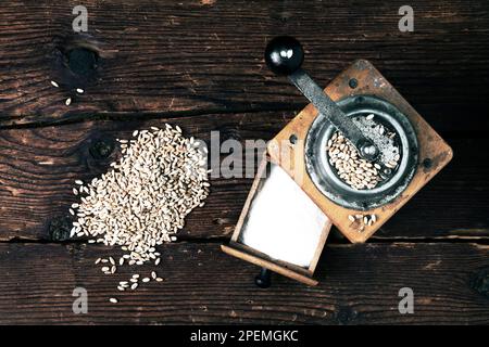 ancien moulin à grain avec grains de blé et farine sur un fond rustique en bois Banque D'Images