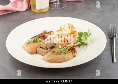 Foie gras de canard à la sauce et pain croustillant sur une assiette en porcelaine blanche Banque D'Images