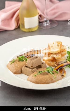 Foie gras de canard à la sauce et pain croustillant sur une assiette en porcelaine blanche Banque D'Images