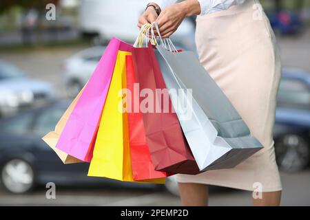 Les mains des femmes tiennent des sacs d'achats multicolores de près Banque D'Images