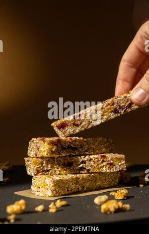 Femme prend le bar énergétique Granola naturel maison. Variété de barres de petit-déjeuner de granola de protéines, avec noix, raisins secs, cerises séchées et chocolat. Nutrition saine alimentation. Collation sans gluten aux céréales Super food Sport Oridge bar Vega dessert concept Banque D'Images