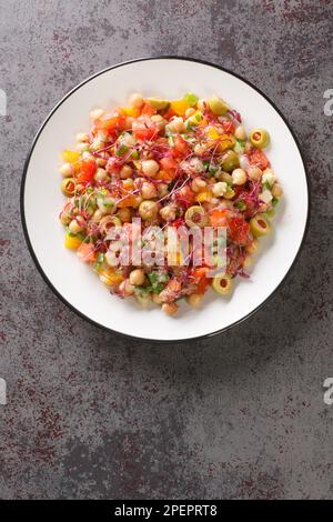 Salade diététique de pois chiches, poivrons, olives, tomates, oignons et vert d'airanthe dans une assiette sur la table. Vue verticale du dessus Banque D'Images