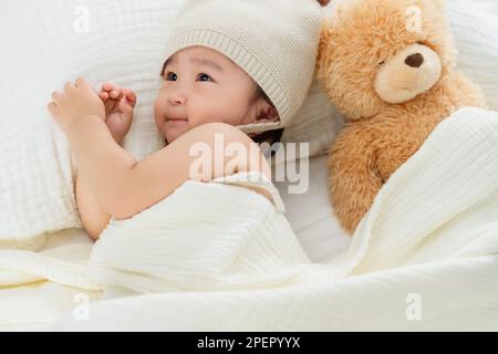 Une petite fille adorable s'allonge sur le lit pour jouer Banque D'Images