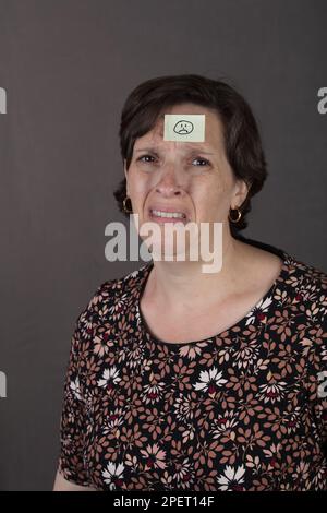 Femme en douleur avec un autocollant triste visage sur sa tête Banque D'Images