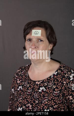 Femme en douleur avec un autocollant triste visage sur sa tête Banque D'Images