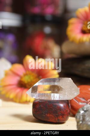 Quartz Crystal équilibré sur Bloodstone avec fleurs en arrière-plan Banque D'Images