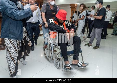 Un agent d'immigration escorte un détenu national nigérian, qui est assis en fauteuil roulant alors qu'il tombe malade pendant la conférence de presse d'expulsion. Les autorités de Bali ont expulsé deux ressortissants britanniques et deux ressortissants nigérians pour surséjour. Le gouverneur de Bali, I Wayan Koster, a annoncé dimanche, 12 mars 2023, Que la politique de visa à l'arrivée (VoA) pour les ressortissants ukrainiens et russes sera révoquée afin de réduire les violations du tourisme, qui sont principalement commises par ces deux nationalités. En 2022, la province de Bali a expulsé 194 étrangers, la majorité pour séjour excessif et travail illégal. Banque D'Images