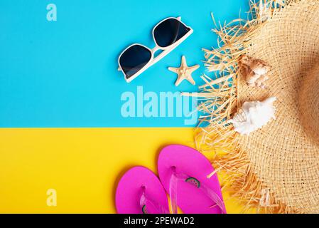 Chapeau de paille lunettes de soleil tongs et coquillages sur fond jaune et bleu planification de voyage de vacances maquette Banque D'Images