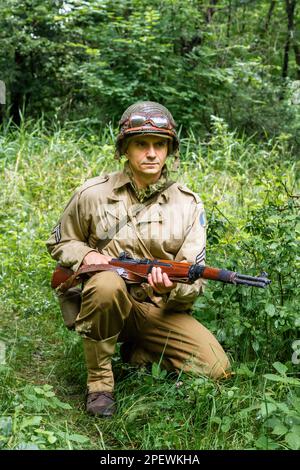 Porabka, Pologne – July18, 2020 : Reeneacteur historique habillé comme soldat d'infanterie américain pendant la Seconde Guerre mondiale patrouillent la forêt. Banque D'Images