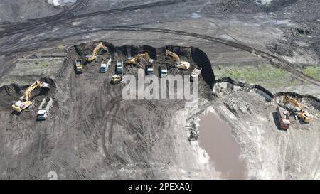 Excavatrices travaillant sur un immense site minier, chargement des tombereaux, camions transport du matériau - vue aérienne. Banque D'Images