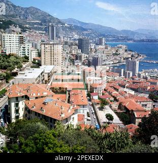 1960s, historique, la Côte d'Azur, l'été et une vue sur les toits de terre cuite de Monaco, avec les blocs luxueux de l'appartement en hauteur de Monte Carlo et son port dans la Méditerranée au loin. Banque D'Images