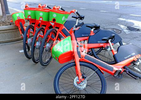 Des vélos verts et orange Lime sont tombés sur un trottoir dans le centre-ville de Cleveland, Ohio, États-Unis. Banque D'Images