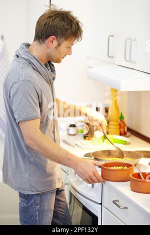 Servir un repas maison sain. Vue latérale d'un jeune homme qui prépare de la nourriture, c'est juste préparé. Banque D'Images
