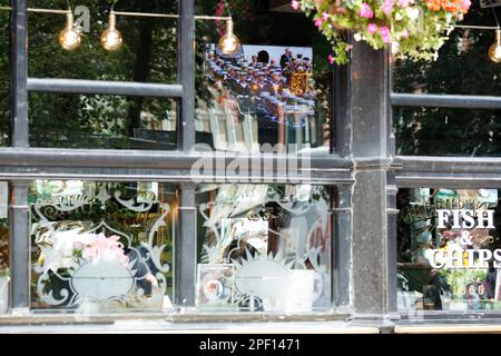 Un écran de télévision affiche la couverture funèbre de feu la reine Elizabeth II dans un pub du centre de Londres, le jour de ses funérailles. Banque D'Images