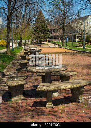 Une rangée de tables en pierre occupe une vieille rue en brique à côté d'un village de l'Ohio commons; chaque table a un damier pour les échecs ou les dames peintes sur son Banque D'Images