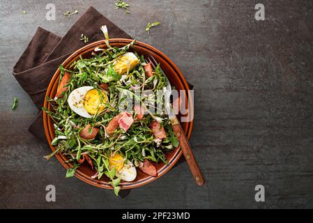 Salade de pissenlits avec œufs et bacon rôti sur fond gris Banque D'Images