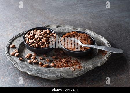 Gros plan sur des grains de café et de la poudre de café fraîchement moulus sur fond de pierre grise Banque D'Images