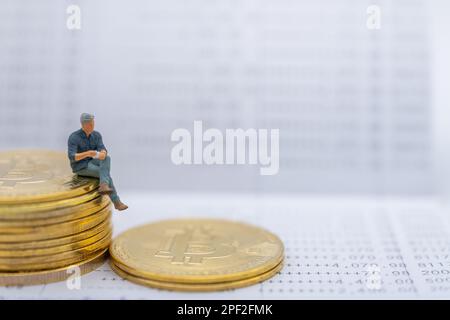 Business, Money, crypto-monnaie et Financial concept. Homme d'affaires miniature figure assise sur une pile de pièces en or Bitcoin sur le livret de banque. Banque D'Images