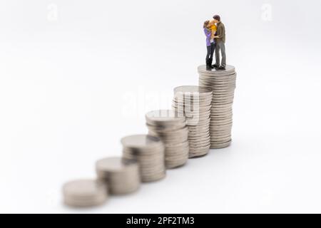 Money, Financial, Business and Family concept, miniature figures homme, femme et enfant se tiennent sur le dessus de la pile de pièces de monnaie sur fond blanc. Banque D'Images