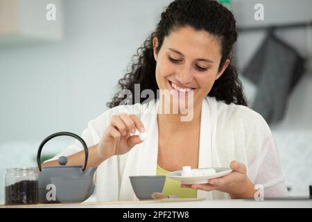 bonne femme qui jette du sucre dans une tasse Banque D'Images