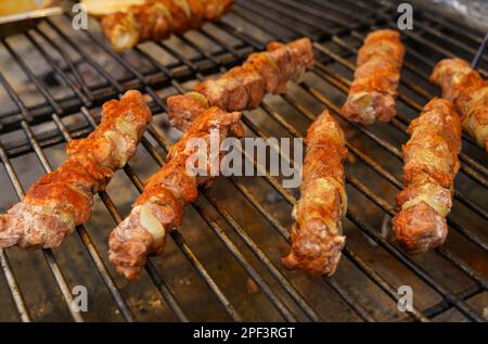 La viande frite avec des oignons sur une brochette repose sur la grille. Cuisine de rue polonaise. Banque D'Images