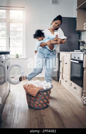 Journée chargée pour cette maman qui travaille. une jeune mère utilisant un téléphone portable tout en effectuant des travaux ménagers et en tenant son bébé à la maison. Banque D'Images