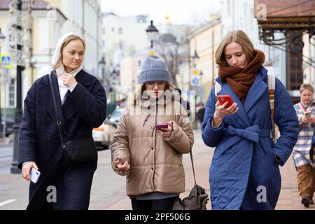 Personnes utilisant un smartphone dans la rue urbaine. Jeunes femmes en vêtements de printemps avec téléphones portables dans les mains Banque D'Images