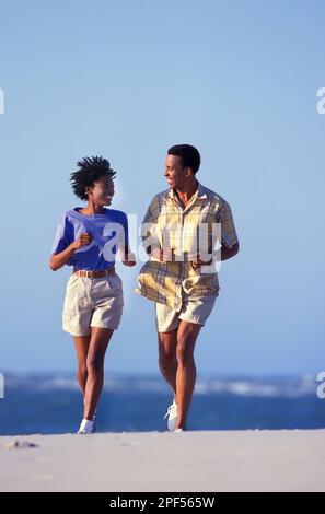 Couple afro-américain qui fait du jogging sur une plage Banque D'Images