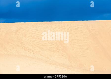Vue sur les dunes de sable du désert sur un ciel bleu ciel nuageux et sombre. Les dunes de Maspalomas à Playa del Ingles, Maspalomas, Grande Canarie, Espagne. Banque D'Images