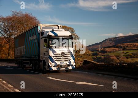 Mercedes Benz Actros tire une remorque de curtainsider le long du A628 Woodhead Pass dans le Yorkshire lors d'un après-midi ensoleillé d'hiver Banque D'Images