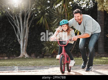 Vous pouvez laisser partir maintenant, papa. un homme qui aide sa fille tout en faisant un vélo. Banque D'Images