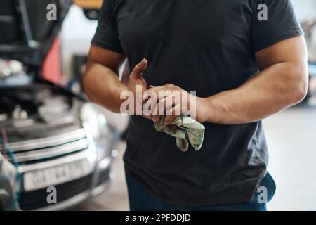 Ça ne me dérange pas de me salir les mains. un mécanicien utilisant un chiffon pour essuyer ses mains sales. Banque D'Images