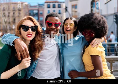 Groupe multiethnique d'amis s'amusant avec des lunettes de soleil en forme de coeur Banque D'Images