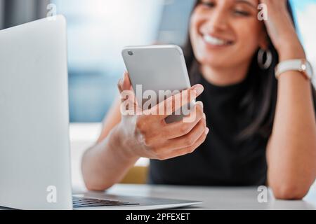 Prendre un moment pour rattraper votre retard sur les réseaux sociaux. une jeune femme d'affaires assise seule au bureau et utilisant son téléphone portable. Banque D'Images