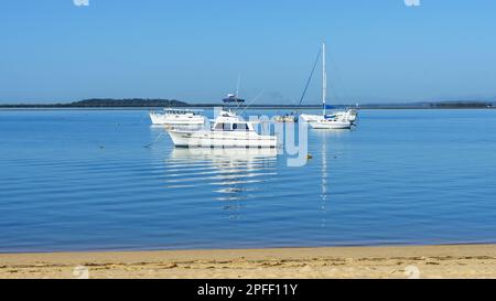 Vue depuis Sandy main Beach sur l'île de Coochiemudlo, en passant par des bateaux ancrés dans l'eau tranquille, pour atterrir à l'horizon Banque D'Images