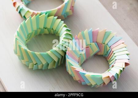 Des anneaux d'origami colorés, des structures paramétriques abstraites en feuilles de papier se trouvent sur un bureau en bois blanc Banque D'Images