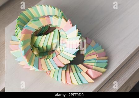 Des anneaux d'origami en papier coloré se trouvent sur une table blanche en bois, structures paramétriques abstraites Banque D'Images