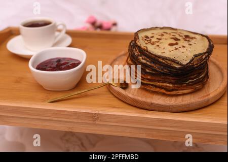 une pile de crêpes avec confiture pour le petit déjeuner. sur la table de petit déjeuner au lit. Banque D'Images