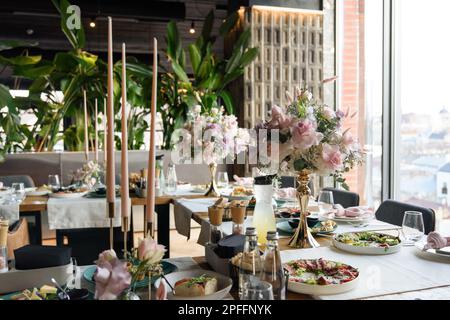 la table servie au restaurant est décorée avec un bouquet luxueux. Roses de jardin, eustoma, populus eucalyptus. couleurs pastel Banque D'Images